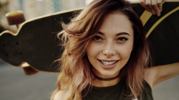 Teen girl holding a skateboard.
