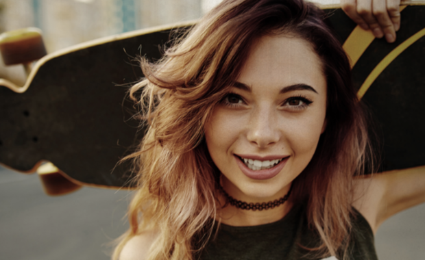Teen girl holding a skateboard.