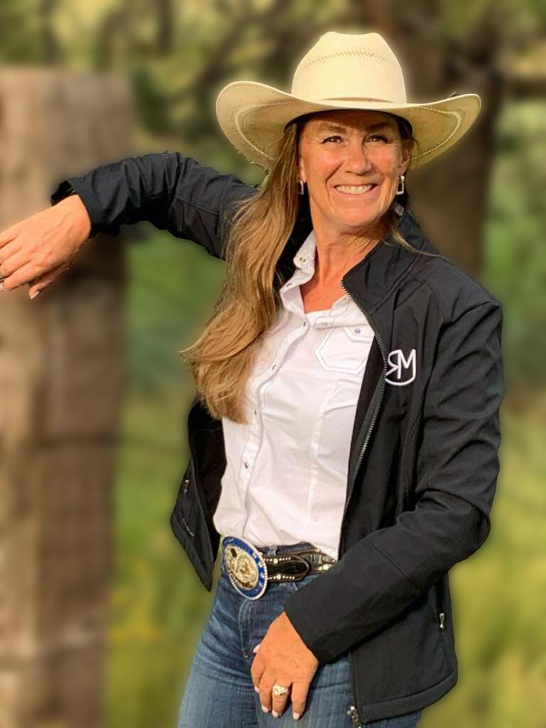 Vanessa standing at a wood fence wearing a cowboy hat.